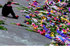 A man sits in front of flowers left in tribute at the Seattle Center International Fountain on September 16.</b></p>